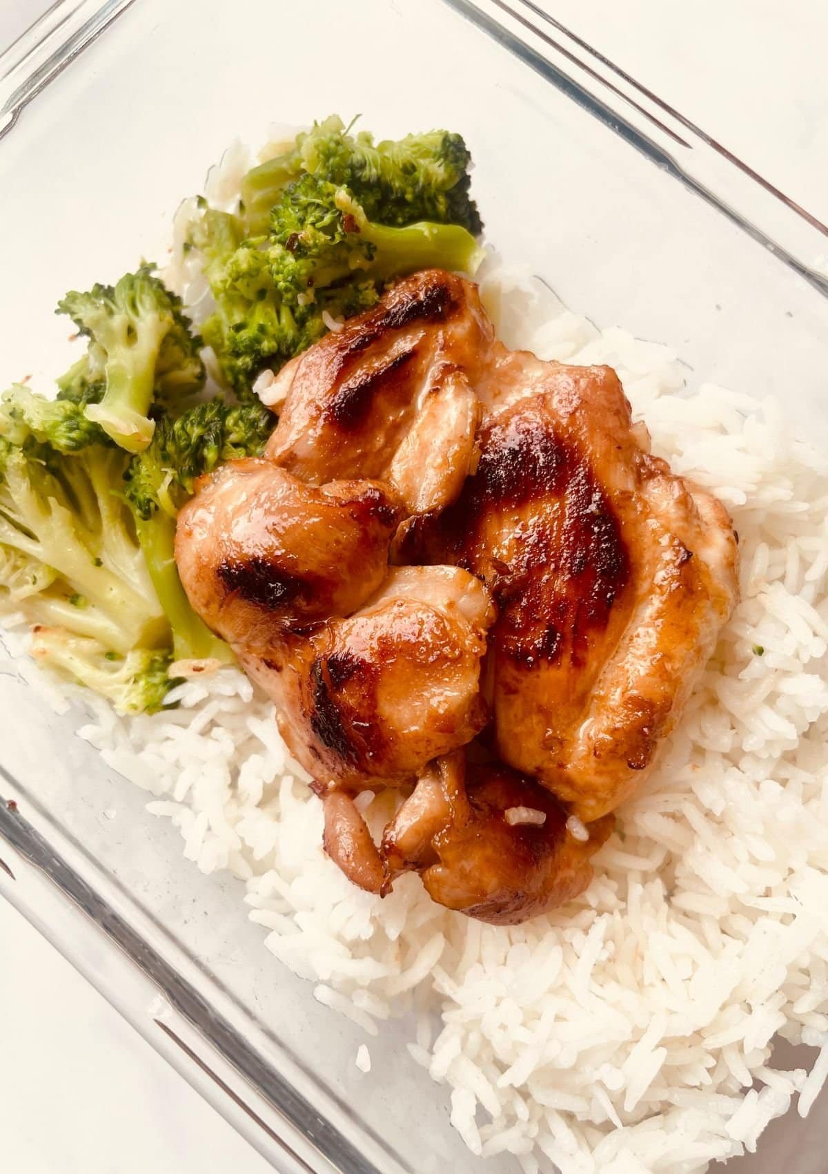 Honey garlic chicken served with steamed broccoli and white rice on a glass dish.