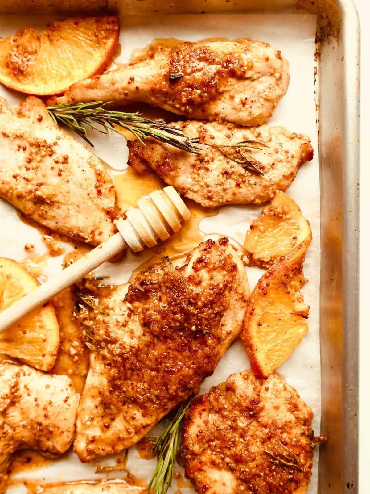 Juicy honey orange Dijon chicken thighs on a sheet pan with roasted potatoes and fresh herbs. Perfec.