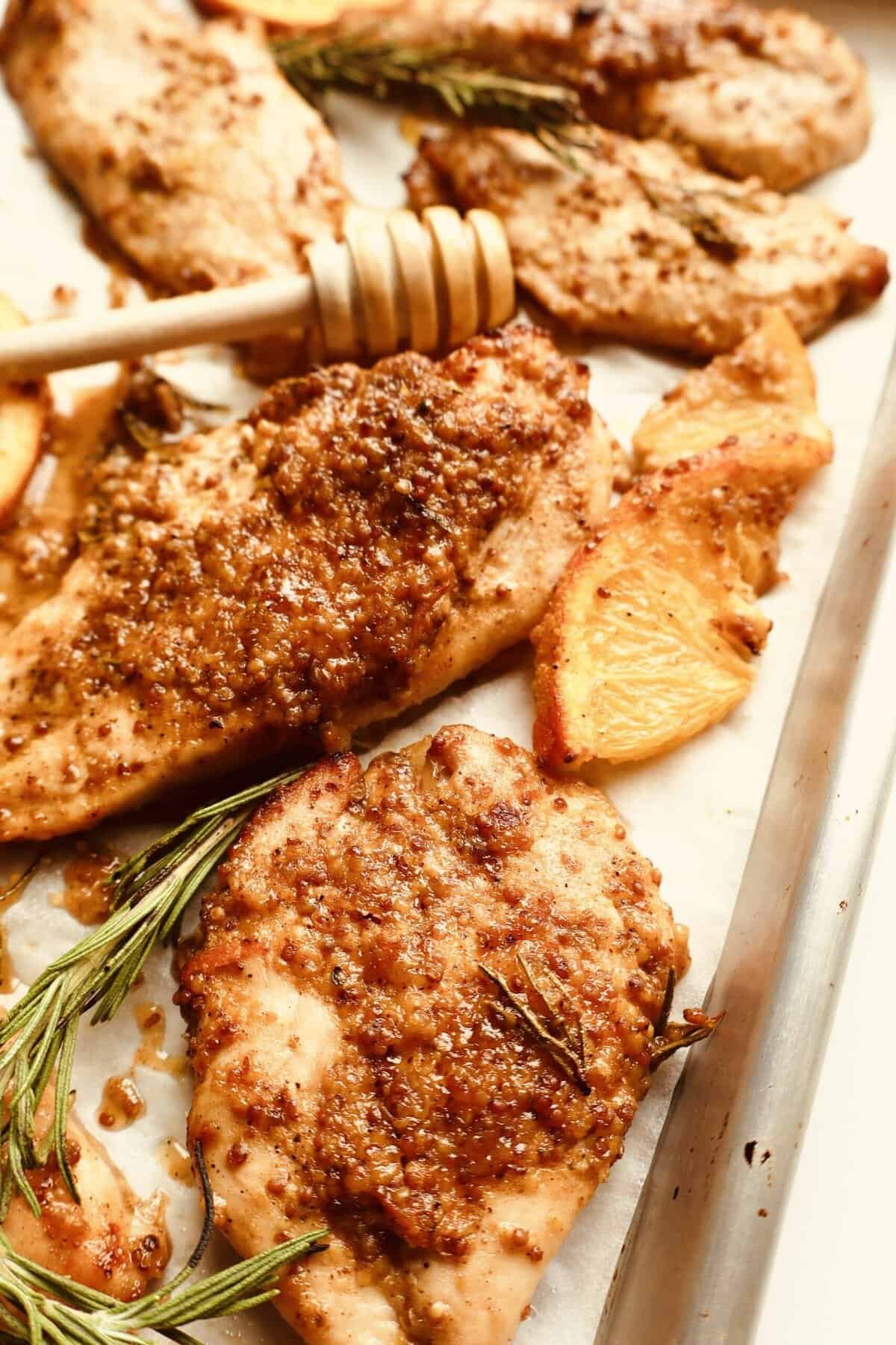 Golden baked chicken thighs with honey orange Dijon glaze on a sheet pan.