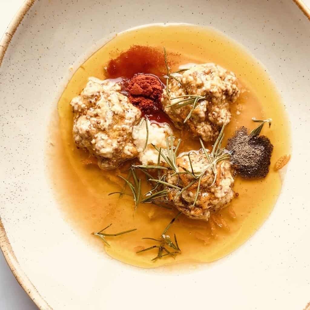 Juicy honey orange dijon chicken with herbs on a white plate.