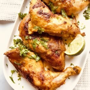 Juicy Middle Eastern yogurt-marinated chicken thighs with fresh herbs and lime wedge.
