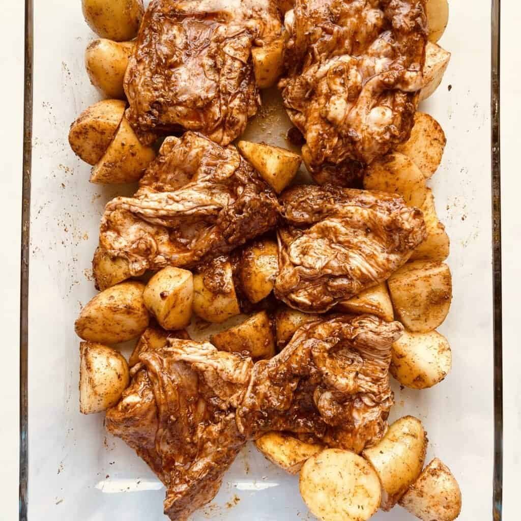 Grilled paprika chicken thighs with roasted potatoes on a baking sheet.