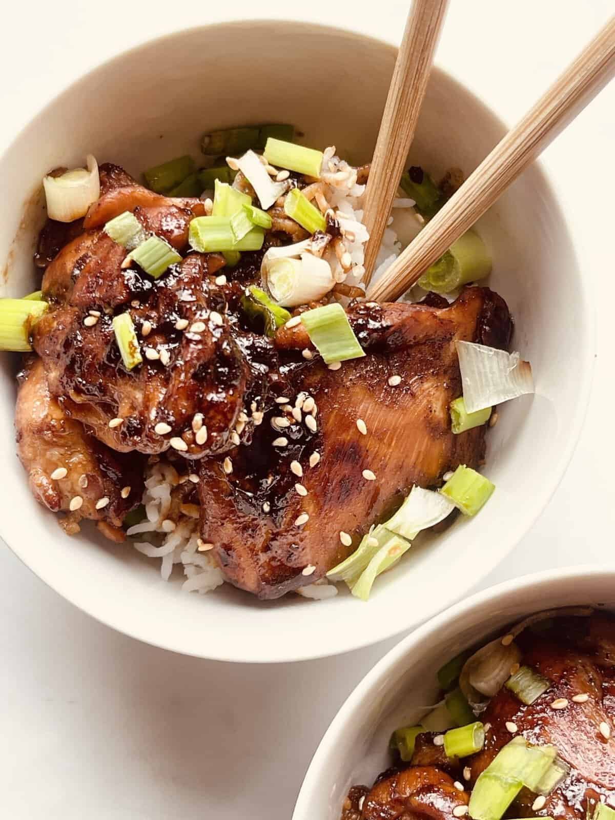 soy garlic chicken with green onions served over rice in a bowl.
