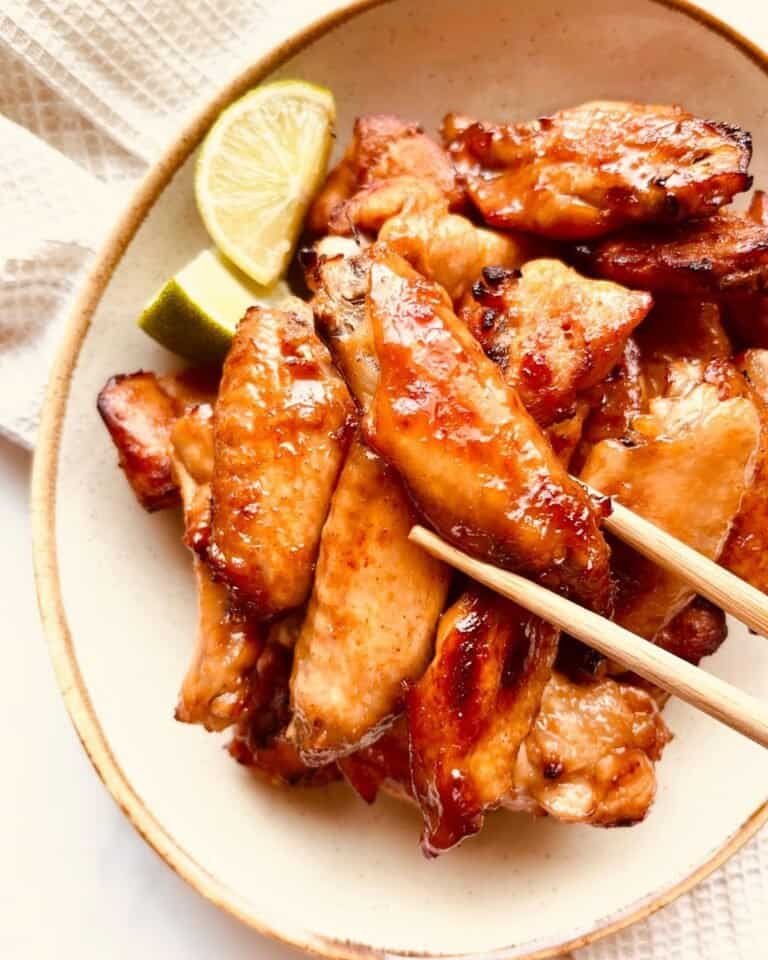 Grilled chicken wings with lemon wedges, glazed with a savory sauce, served in a rustic bowl for a d.