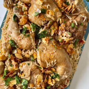 Golden roasted chicken thighs topped with toasted almonds and fresh herbs, served over rice.