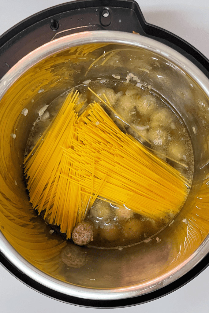 Boiling spaghetti with meatballs in a rice cooker for easy pasta dinner.
