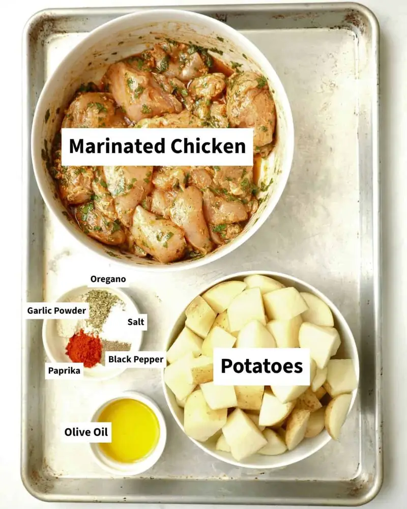 Fresh ingredients for Dump and Bake Mediterranean Chicken and Potatoes—marinated chicken, baby potatoes, garlic, lemon, herbs, and warm Mediterranean spices, all prepped and ready to cook.