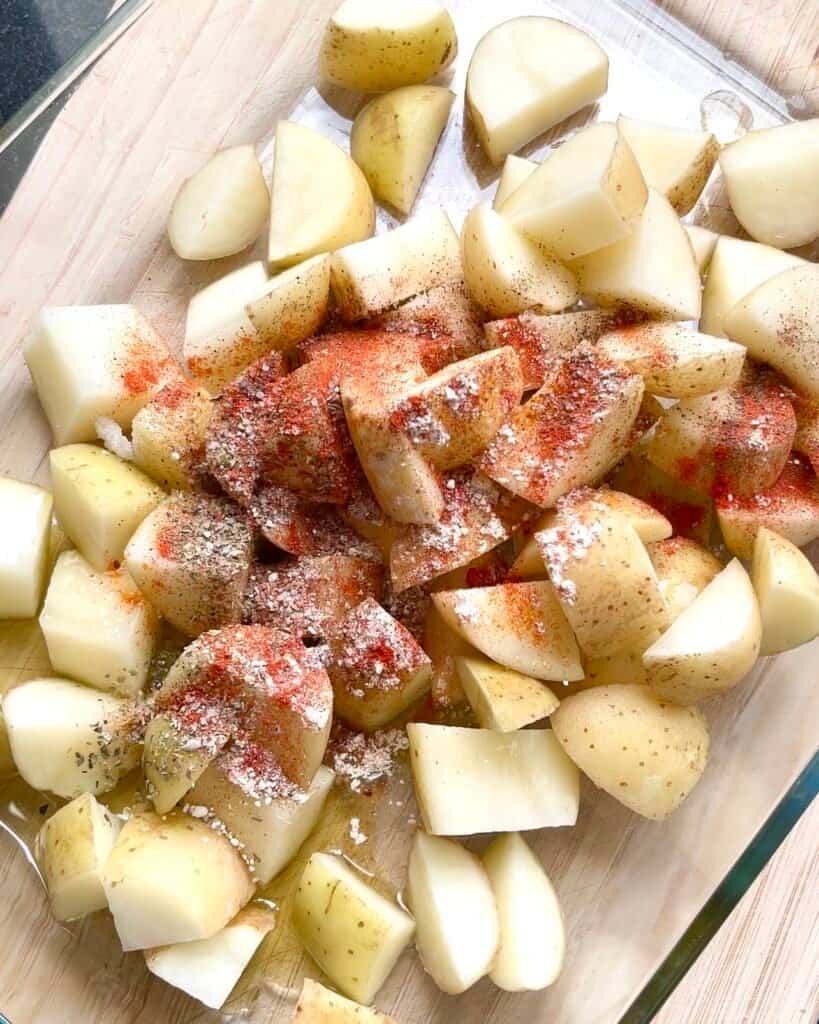 Seasoned baby potatoes in a baking dish, coated with olive oil, garlic, paprika, and oregano—ready to be baked into the perfect Dump and Bake Mediterranean Chicken and Potatoes.