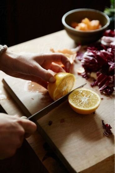Sliced lemon being prepared on a wooden cutting board for a fresh recipe.