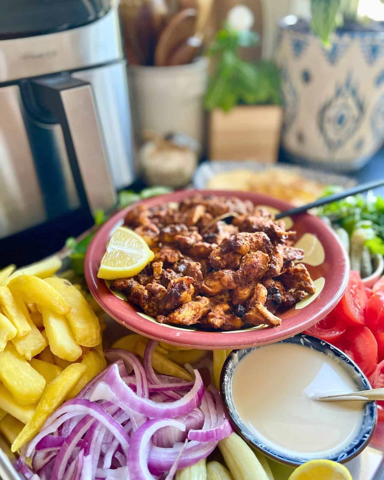 Grilled chicken shawarma served with fresh vegetables and creamy garlic sauce on a colorful plate.