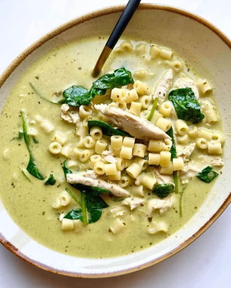 Creamy chicken pesto soup with pasta and spinach in a bowl, ready to serve.