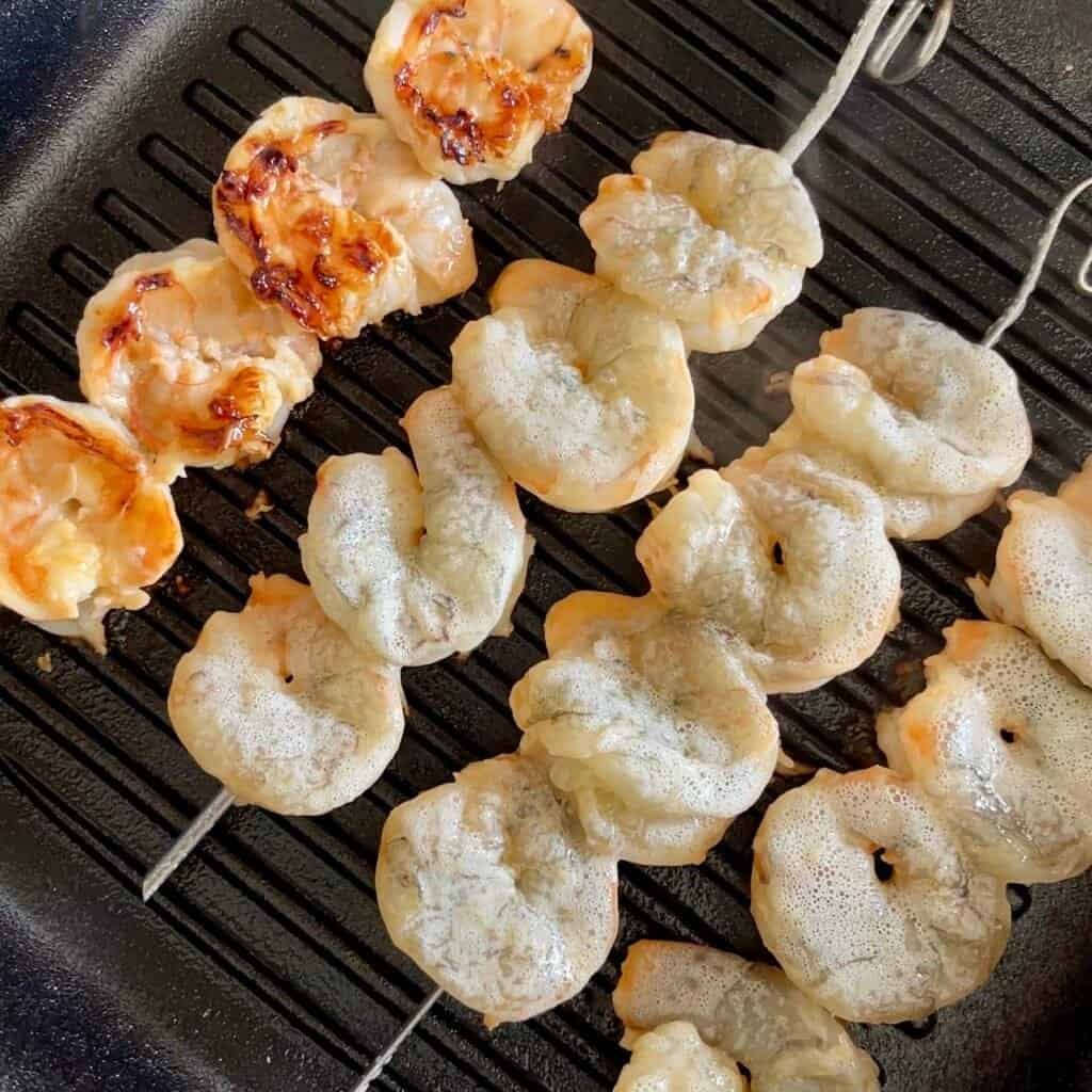 Grilled shrimp skewers with honey garlic marinade on a barbecue grill.