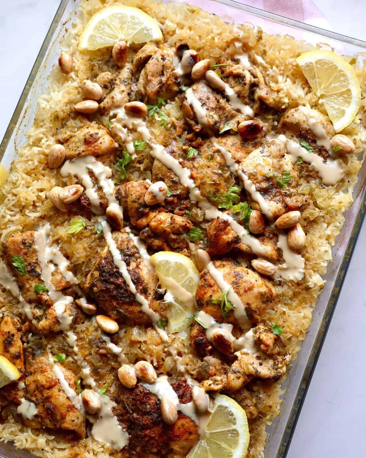 Grilled Mediterranean chicken and rice bake with lemon, pine nuts, and creamy sauce in a glass dish.