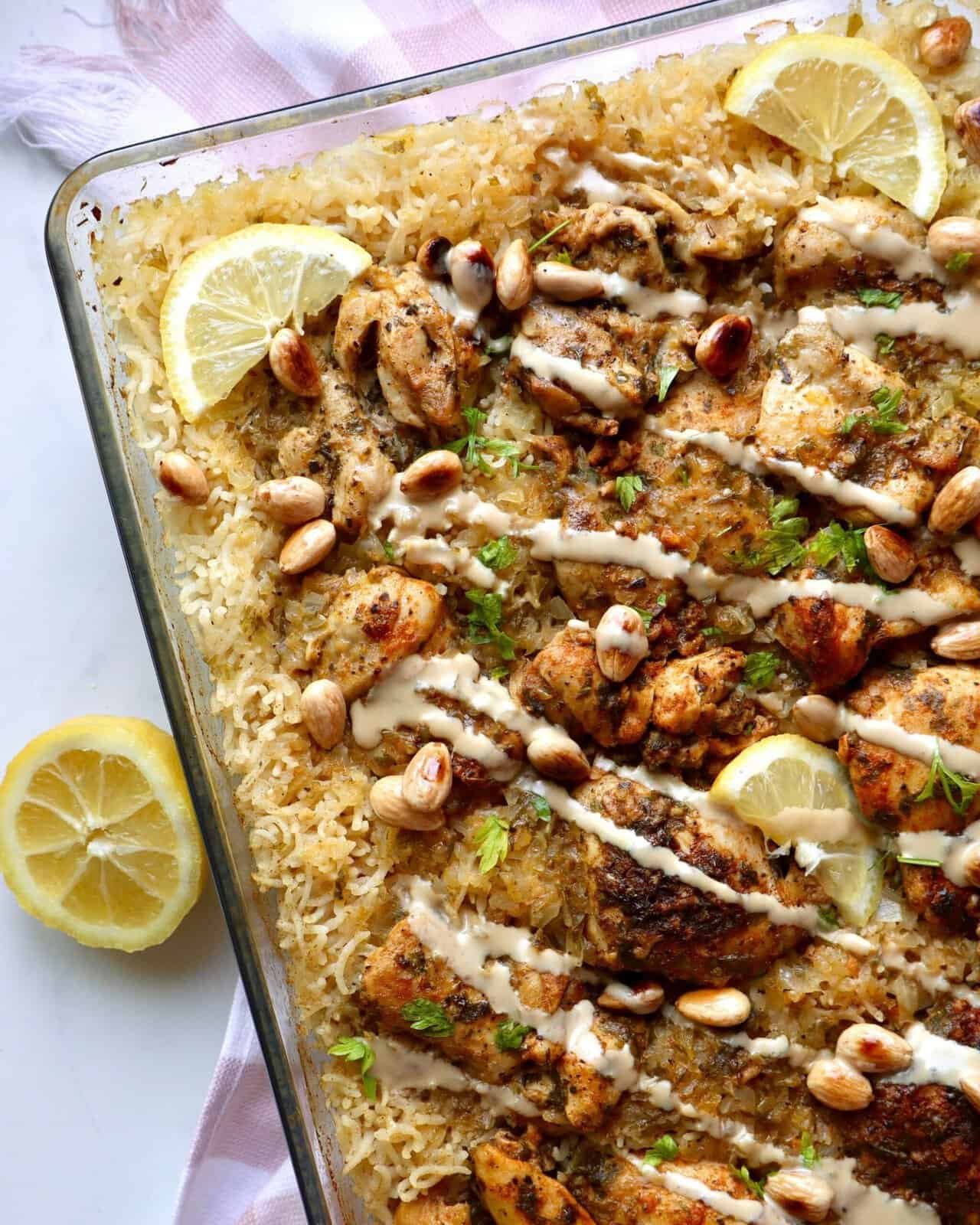 Juicy Mediterranean chicken and rice bake with lemon, pine nuts, and herbs in a glass dish.