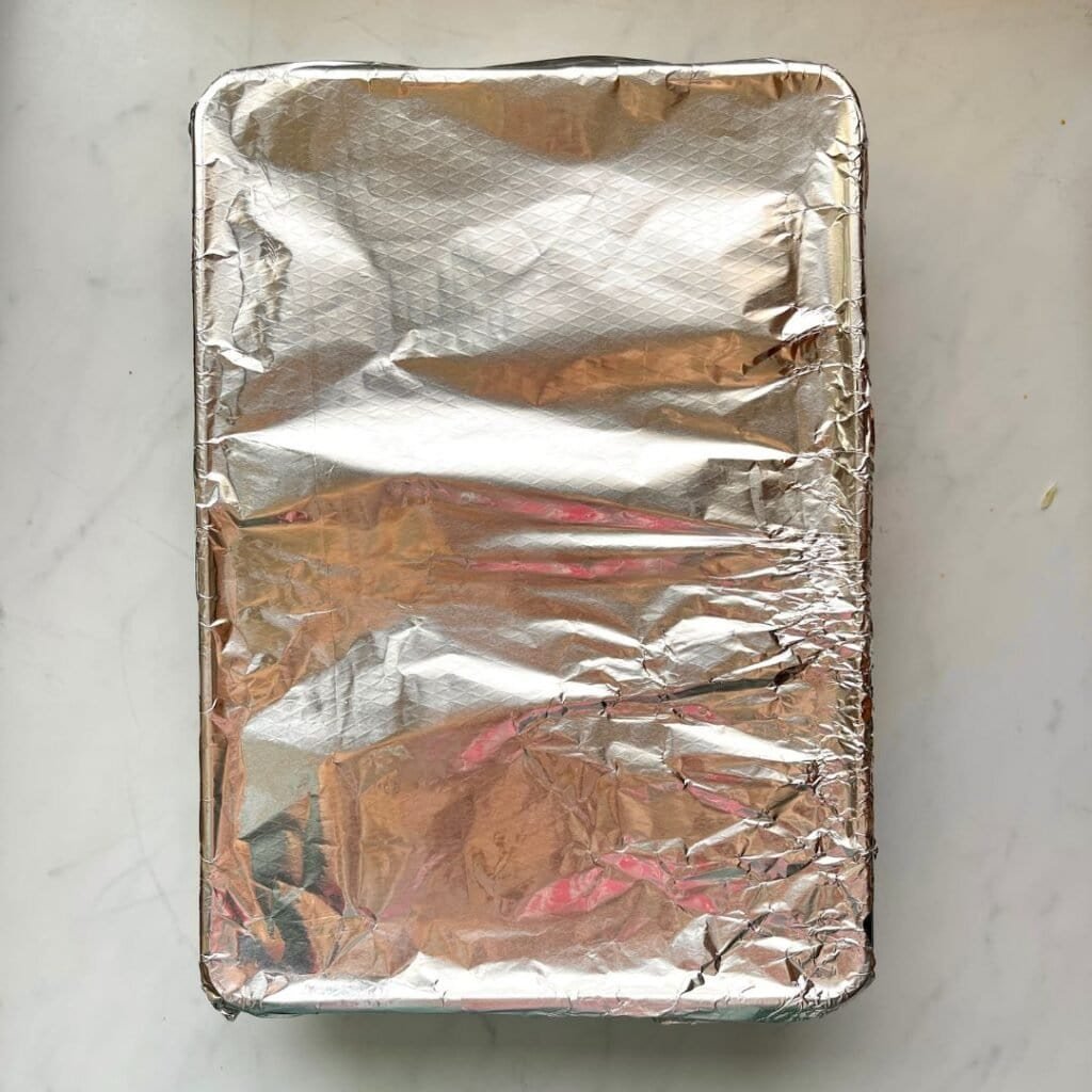 Grilled Mediterranean chicken and rice bake wrapped in foil, ready for baking or serving.