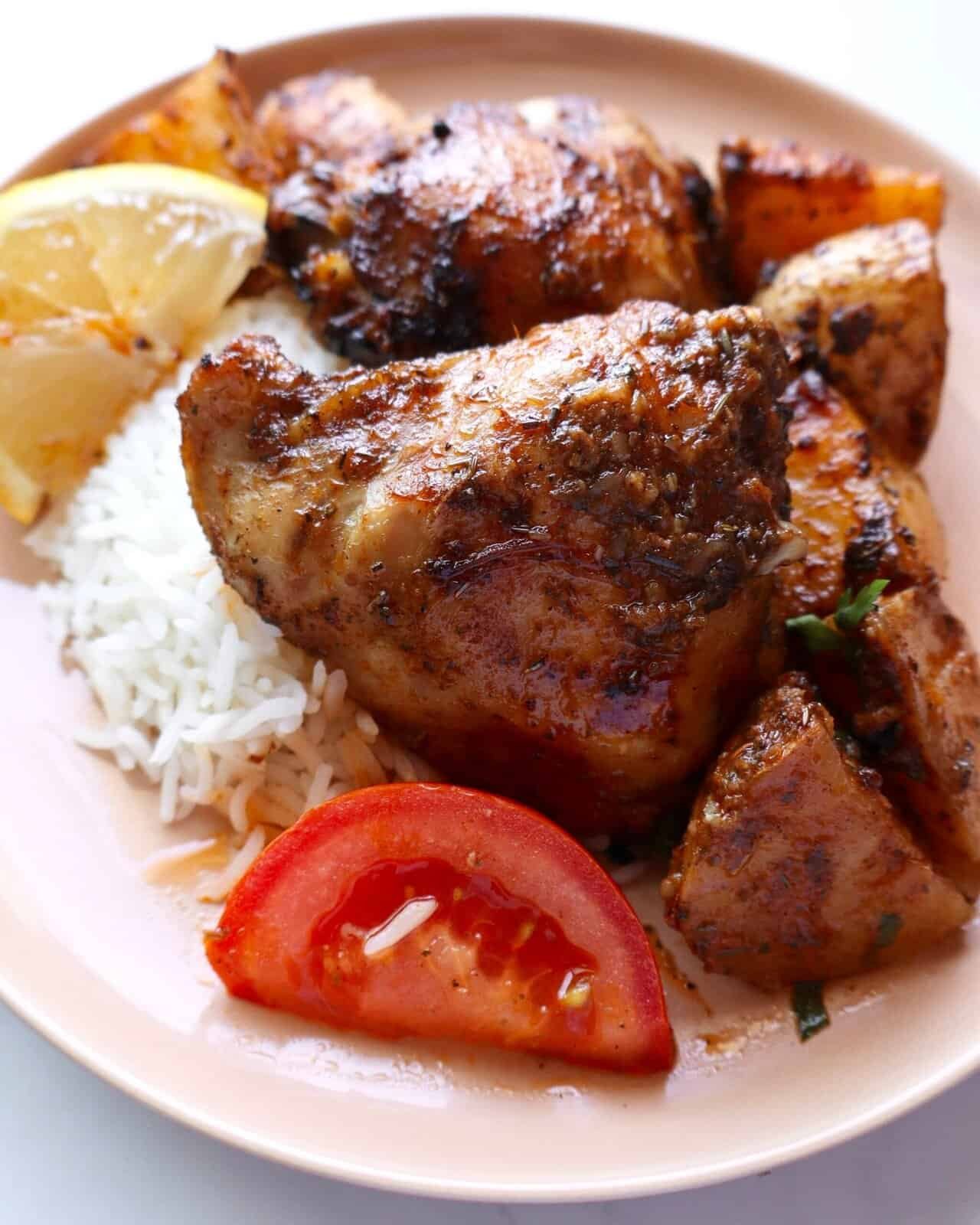Juicy paprika chicken marinade served with rice, lemon, and fresh tomato slices for a flavorful meal.