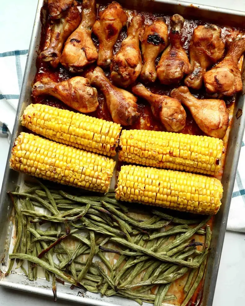 Juicy BBQ chicken drumsticks glazed in sticky smoky sauce, roasted with sweet corn on the cob and green beans on one sheet pan—easy, family-friendly weeknight dinner with bold caramelized flavor.