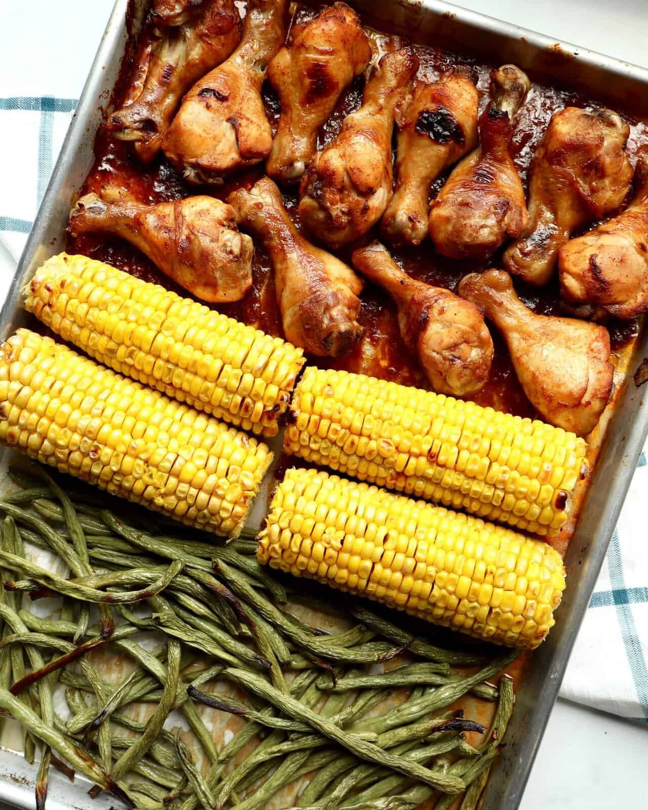 Juicy BBQ chicken drumsticks glazed in sticky smoky sauce, roasted with sweet corn on the cob and green beans on one sheet pan—easy, family-friendly weeknight dinner with bold caramelized flavor.