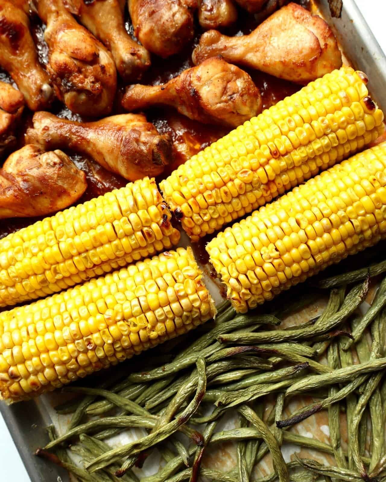Juicy BBQ chicken drumsticks glazed in sticky smoky sauce, roasted with sweet corn on the cob and green beans on one sheet pan—easy, family-friendly weeknight dinner with bold caramelized flavor.