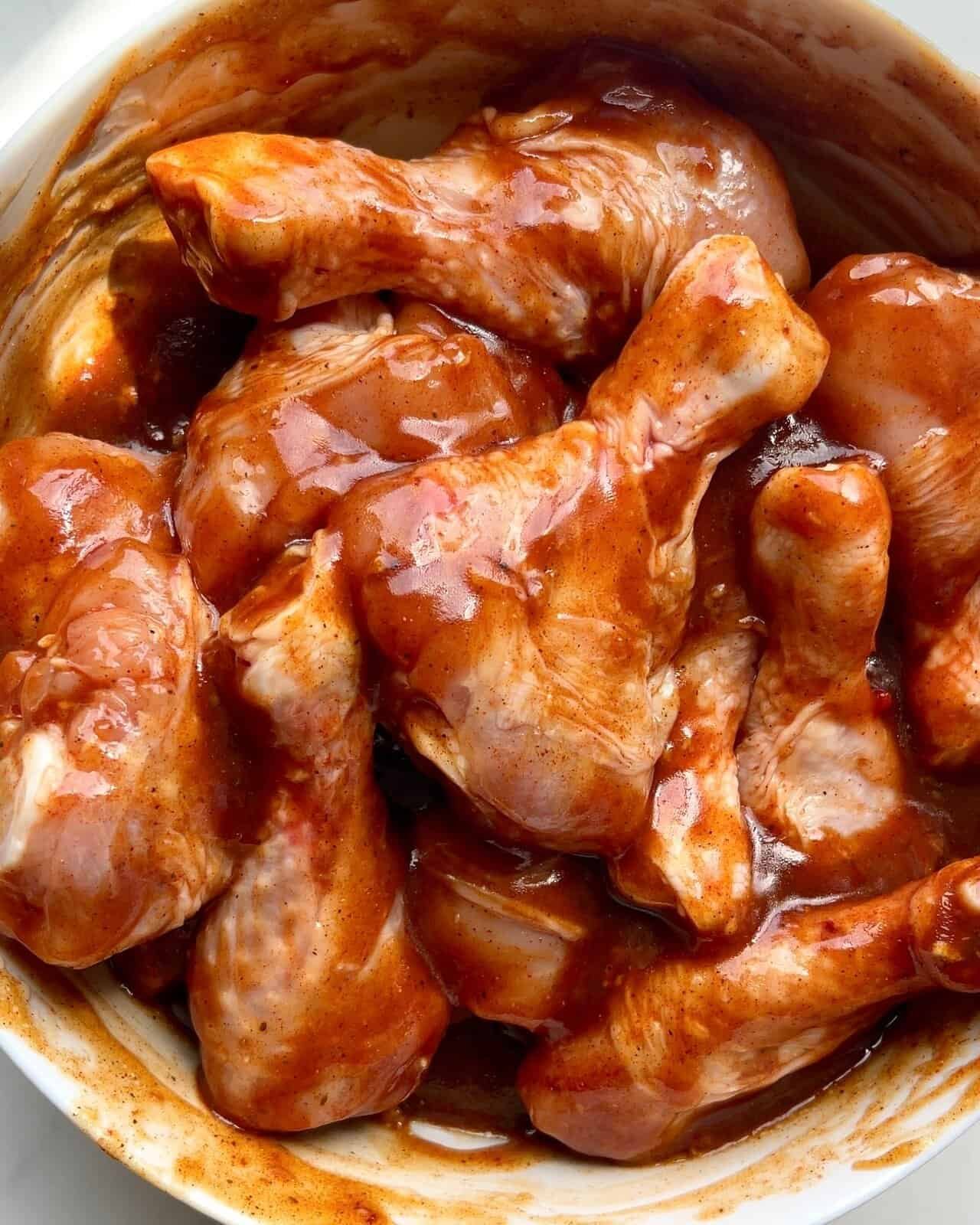 Grilled BBQ chicken drumsticks with vegetables on a sheet pan.