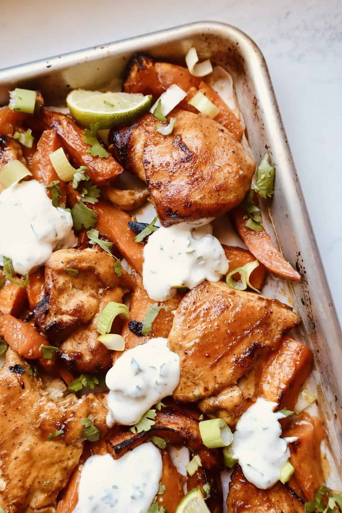 Honey chili glazed chicken baking on sheet pan with sweet potatoes.