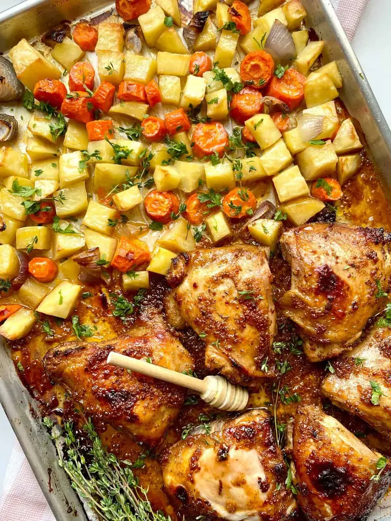 Juicy honey Dijon chicken thighs with roasted vegetables on a sheet pan. Perfect easy dinner recipe.