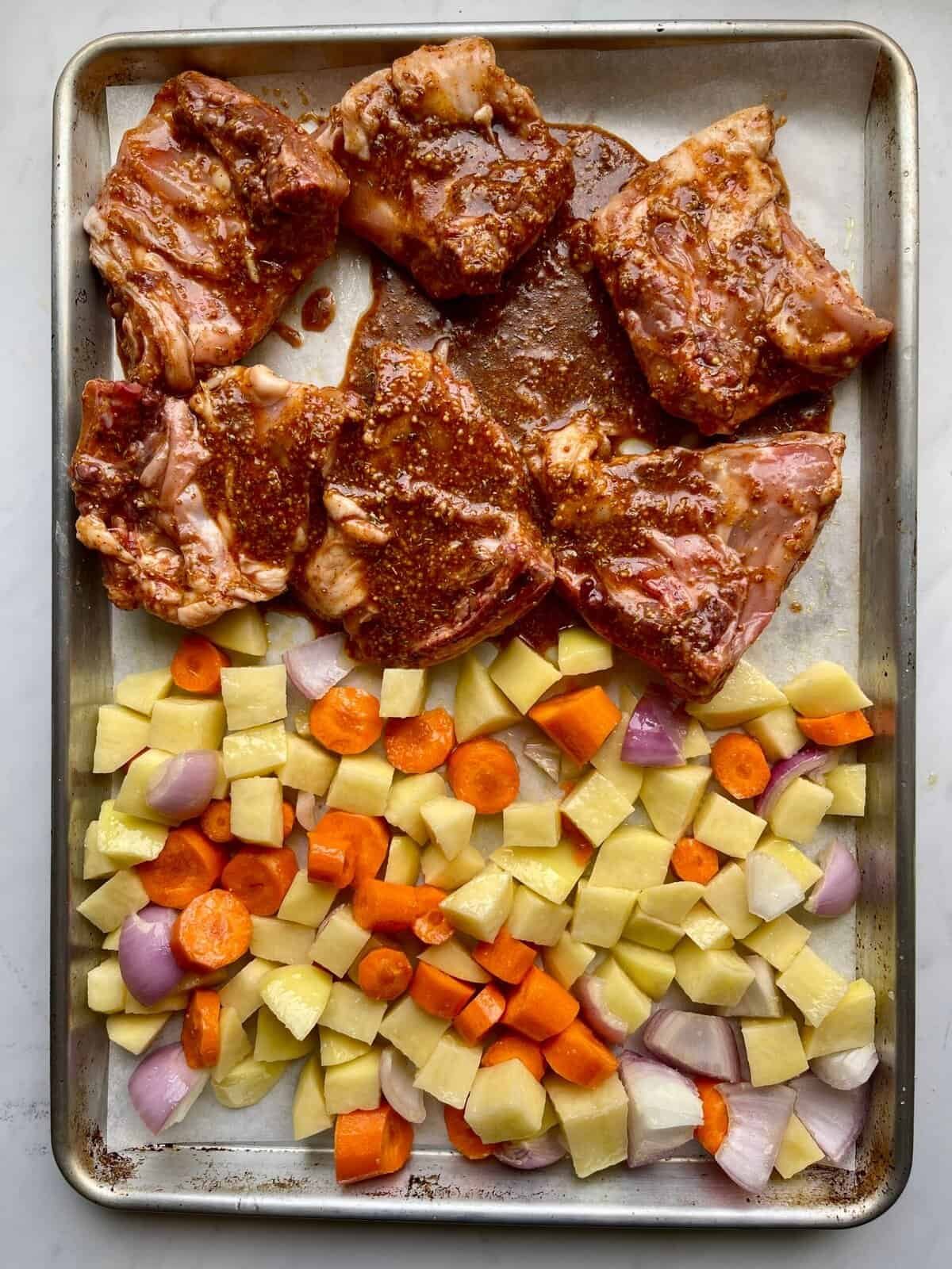 Juicy honey Dijon chicken thighs with roasted vegetables on a baking sheet. Perfect for easy, flavor.