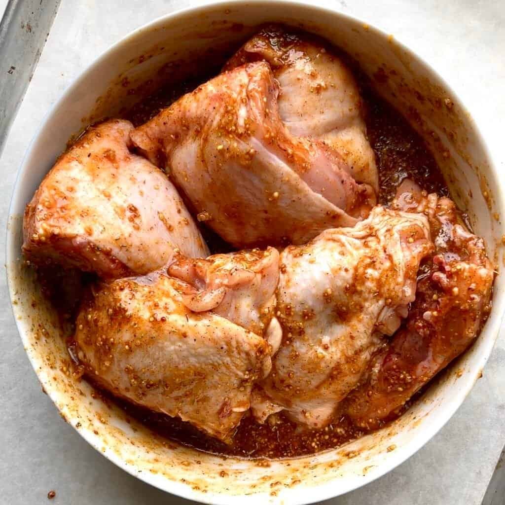 Grilled chicken thighs with honey Dijon glaze and spices in a white bowl.