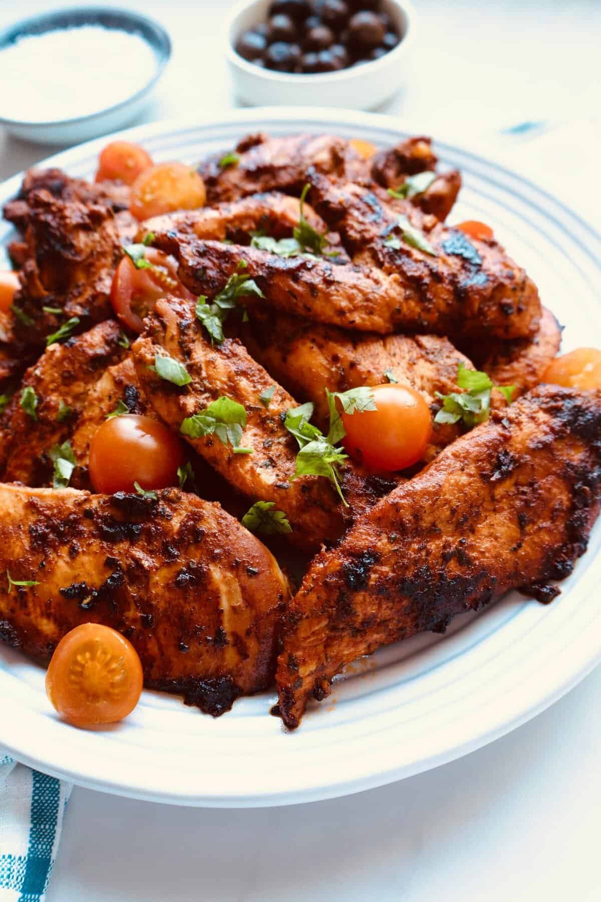 Tomato herb chicken marinade with fresh herbs and cherry tomatoes on a plate.