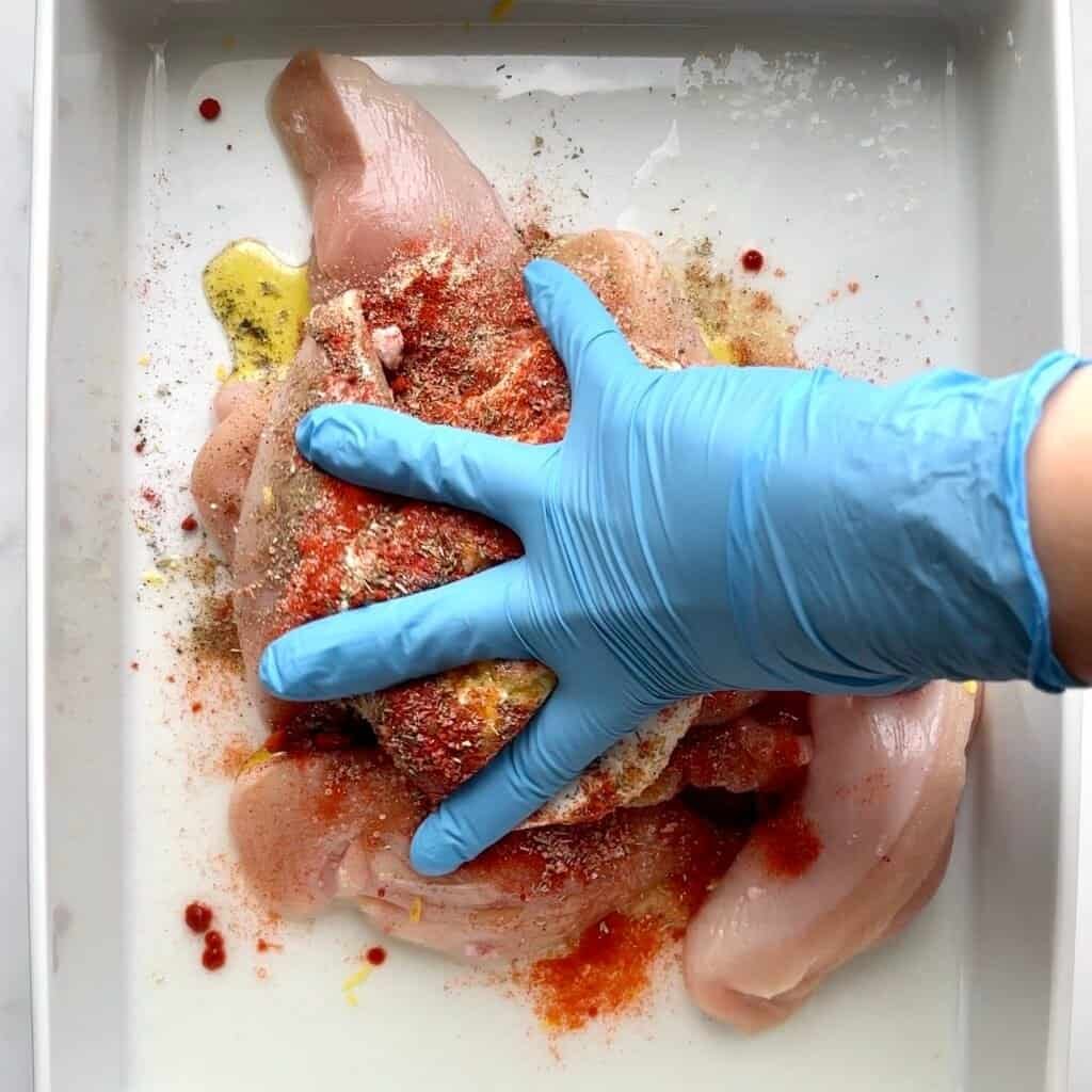 Raw chicken breasts seasoned with spices and herbs, ready for cooking.