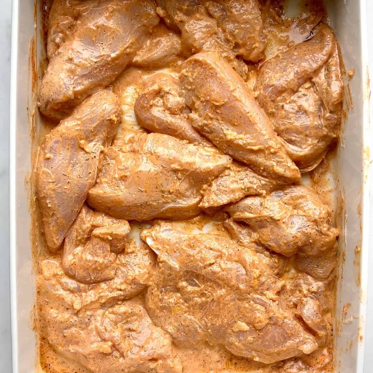 Juicy marinated chicken thighs ready for baking in a creamy spice sauce. Perfect for flavorful, easy.