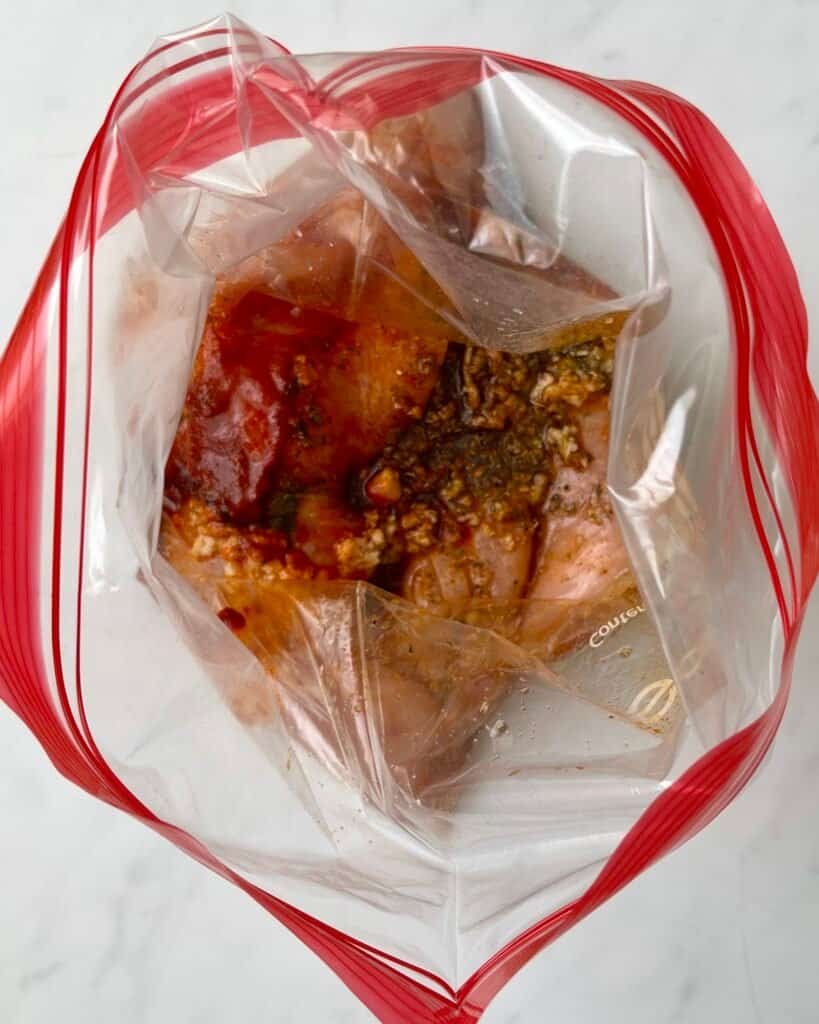 chicken marinating in a sealed bag for easy oven cooking