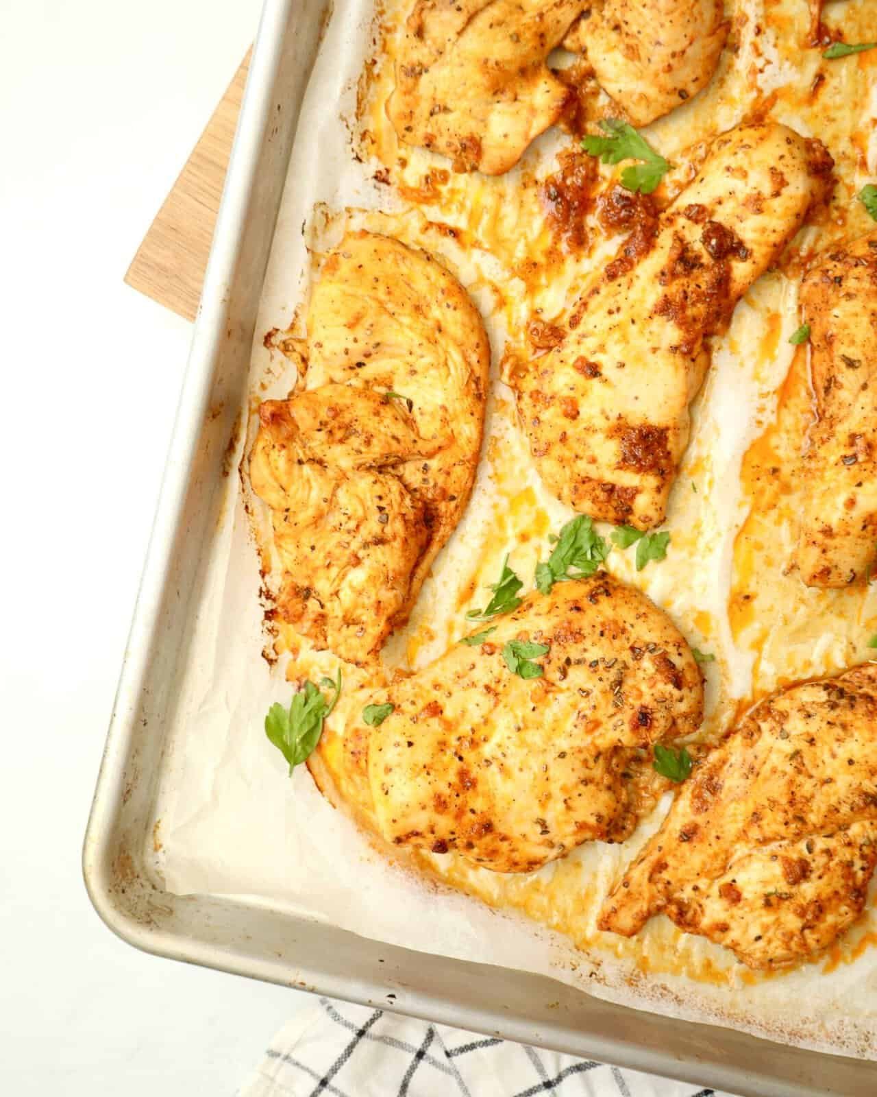Juicy oven baked chicken breast on a tray with golden edges 