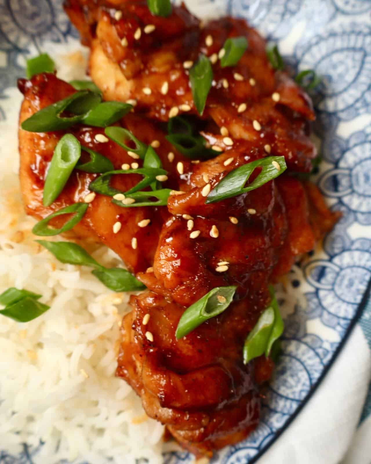 Sweet and spicy glazed chicken served with fluffy white rice, garnished with green onions and sesame.