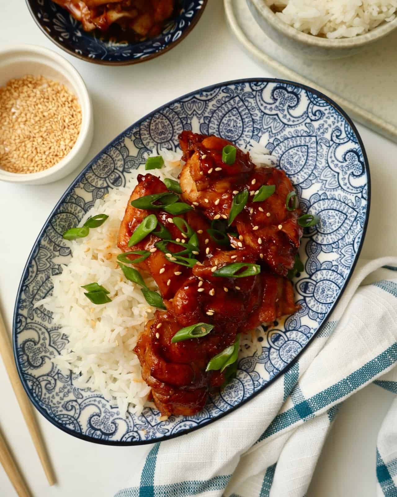 Korean-style gochujang chicken served with rice, sesame seeds, and green onions.