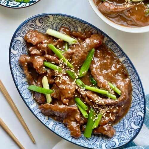Instant Pot Mongolian Beef served over white rice with glossy sweet and savory sauce and green onion garnish