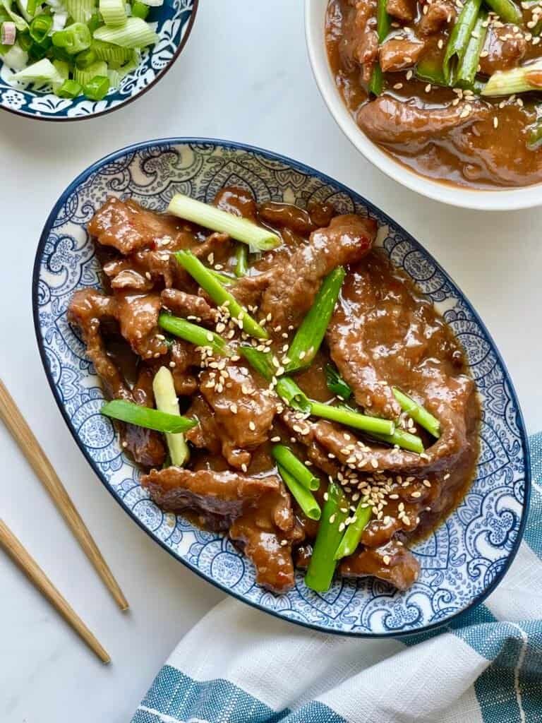 Instant Pot Mongolian Beef served over white rice with glossy sweet and savory sauce and green onion garnish