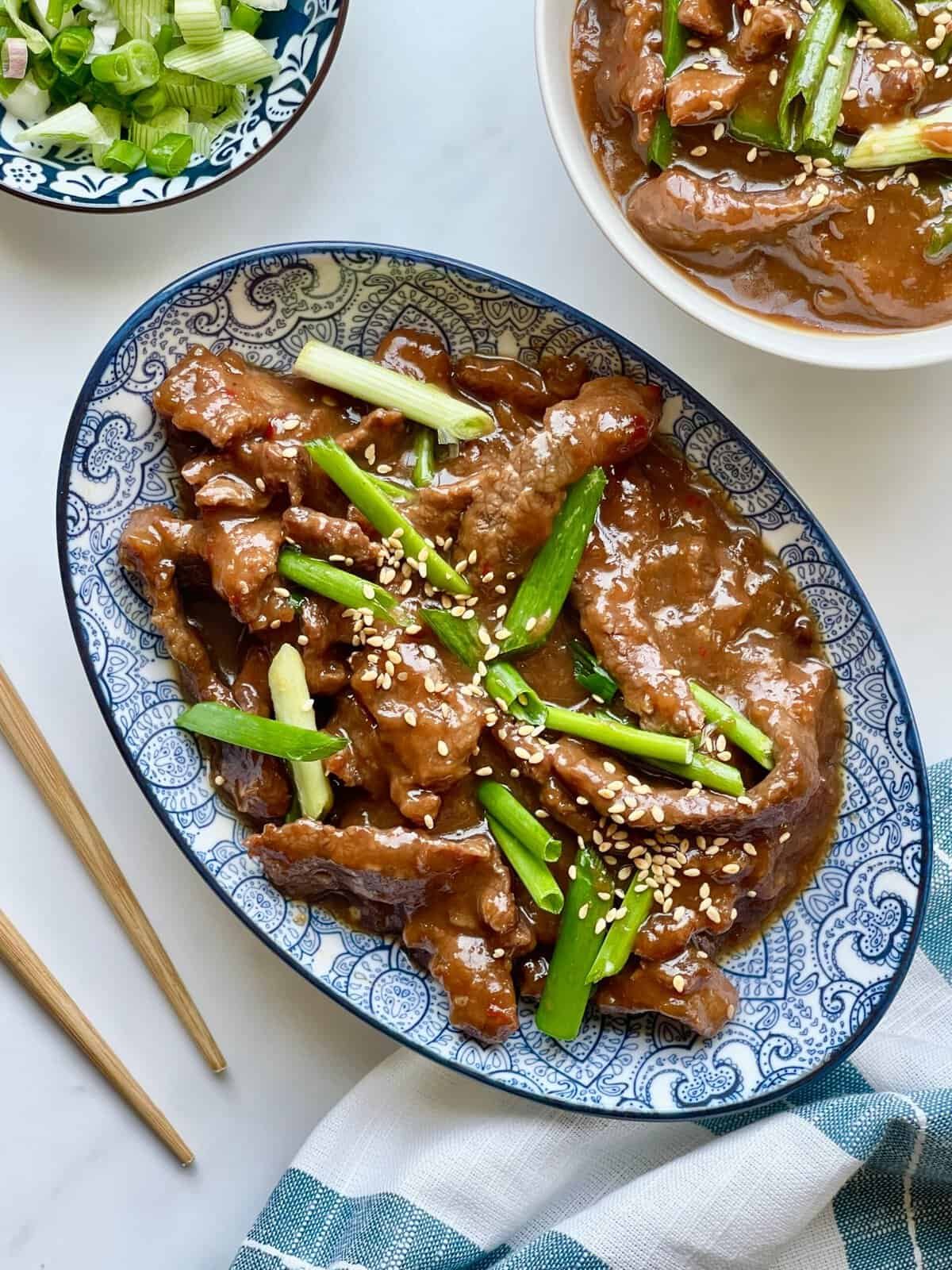 Instant Pot Mongolian Beef served over white rice with glossy sweet and savory sauce and green onion garnish