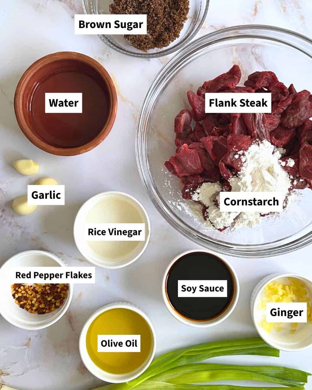 Ingredients for Instant Pot Mongolian Beef laid out on a counter including flank steak, soy sauce, garlic, ginger, and brown sugar