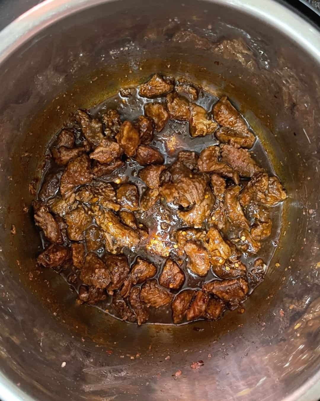 Beef and sauce mixture inside Instant Pot before cooking sealed and ready for pressure cooking