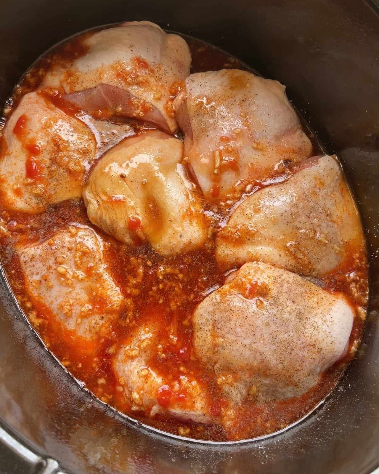 Chicken thighs cooking in soy garlic sauce in a slow cooker, ready to be served.