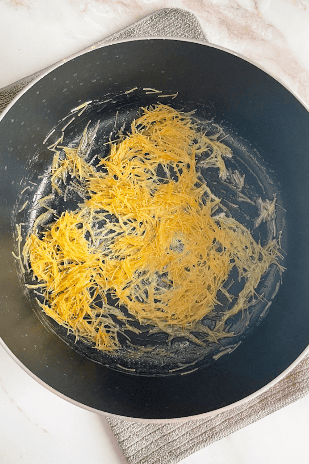 Vermicelli noodles lightly toasting in olive oil in a pot, early stage before turning golden for Lebanese rice
