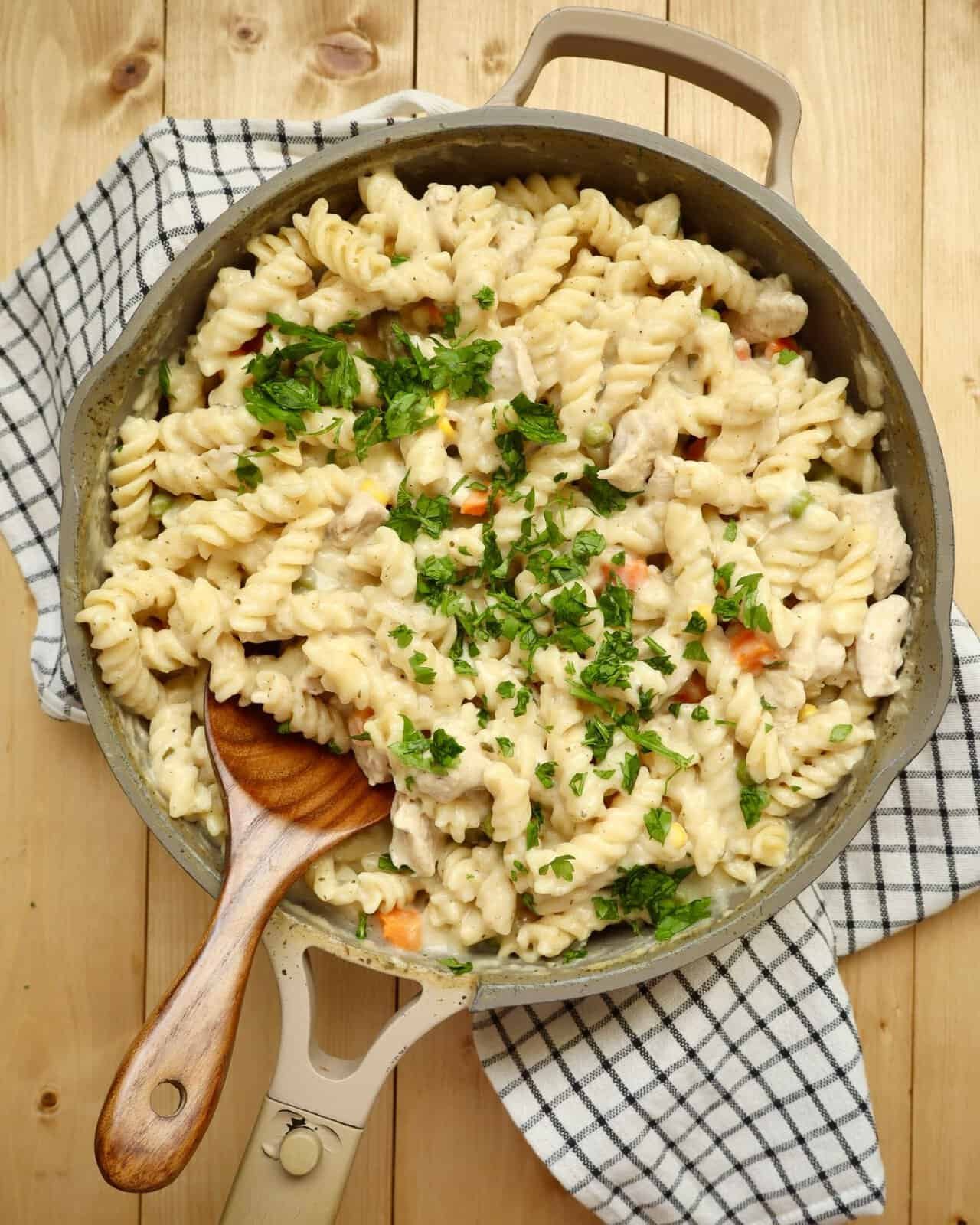 Creamy One Pot Chicken Alfredo Pasta with chicken, vegetables, and melted cheese served in a deep skillet.