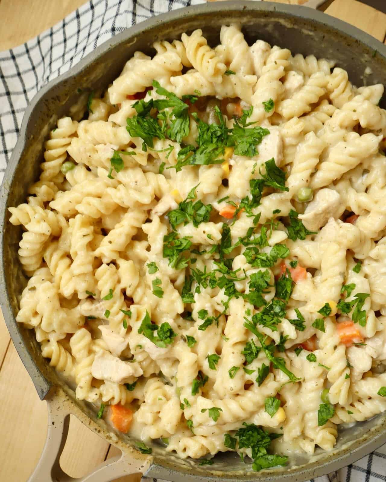 Homemade One Pot Chicken Alfredo Pasta garnished with parsley and Parmesan in the skillet it was cooked in.