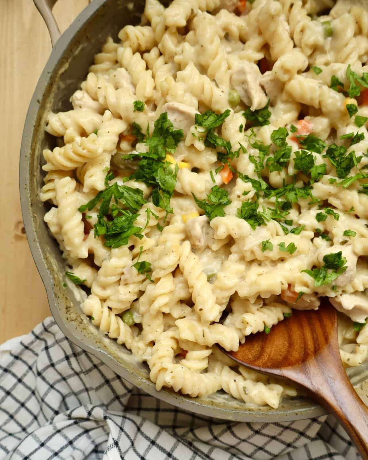 Close-up of creamy One Pot Chicken Alfredo Pasta cooked in a deep skillet with melted mozzarella and Parmesan cheese.