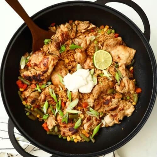 Grilled chicken stir-fry with vegetables, lime, and sour cream in a black skillet. Perfect for a qui.