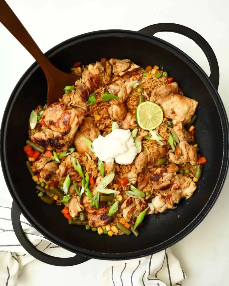 Grilled chicken stir-fry with vegetables, lime, and sour cream in a black skillet. Perfect for a qui.