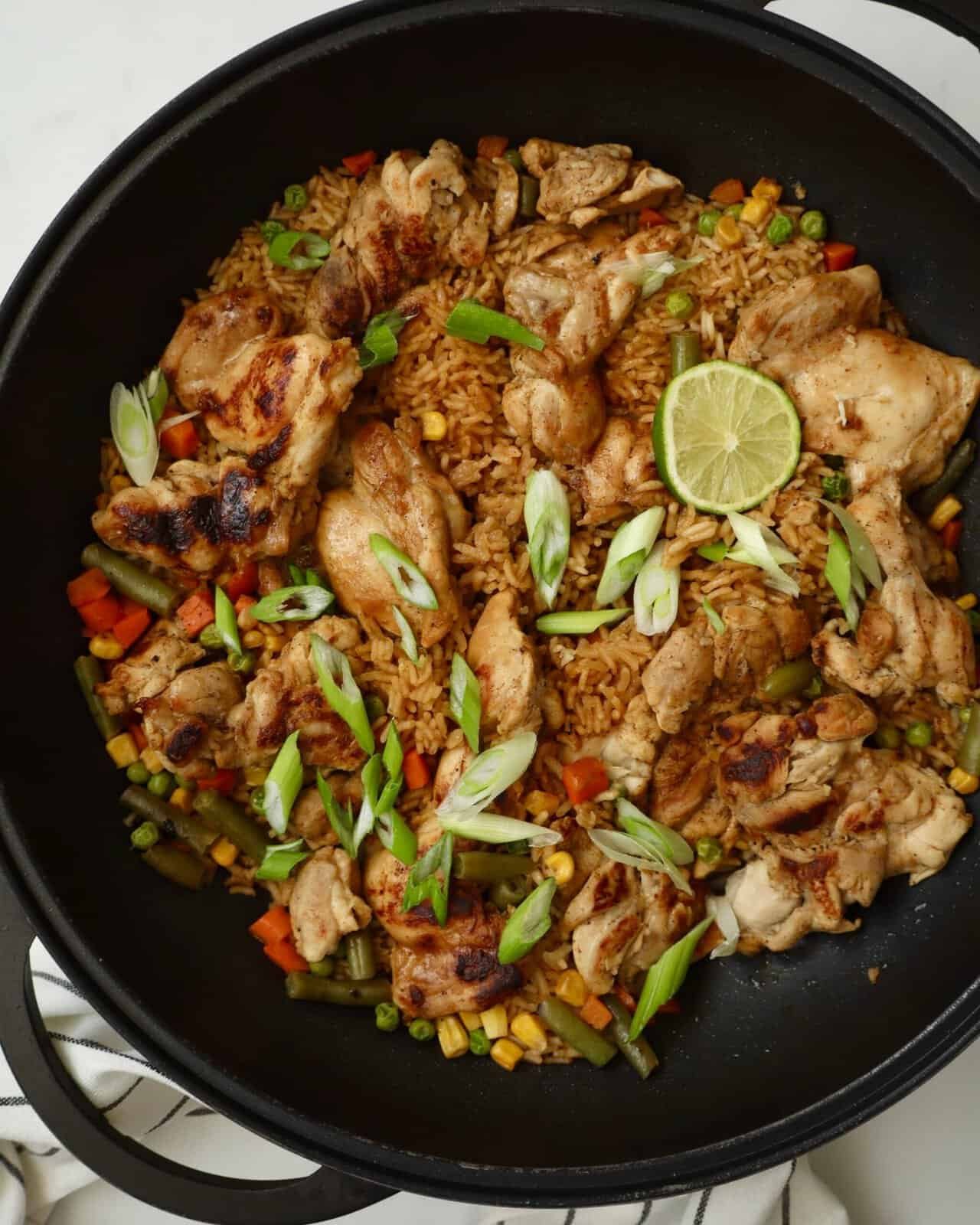 Easy one pan chicken and rice dinner made with sticky garlic lime chicken thighs, sweet corn, and creamy lime drizzle