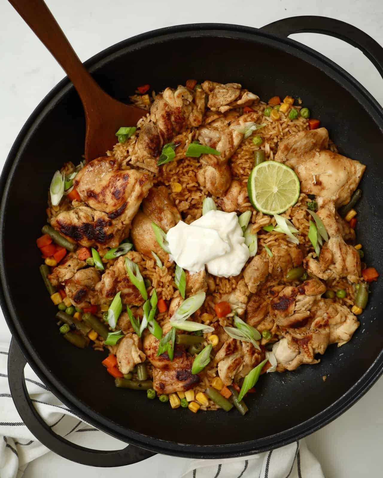Easy one pan chicken and rice dinner made with sticky garlic lime chicken thighs, sweet corn, and creamy lime drizzle.